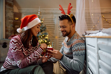 Young couple enjoys in cup of hot chocolate with marshmallows during winter holidays at home.