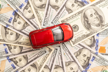 American dollars and miniature car model on white wooden background. Car loan concept