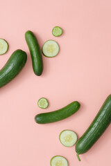 Fresh cucumbers and round cucumber slices are randomly decorated on a blank background. Minimalist scene for a food or cosmetics advertisement involving cucumbers.