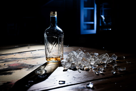 An alcohol kills. An empty alcohol bottle on a table on a dark background. The concept of alcohol dependence. An empty alcohol bottle on the table 
