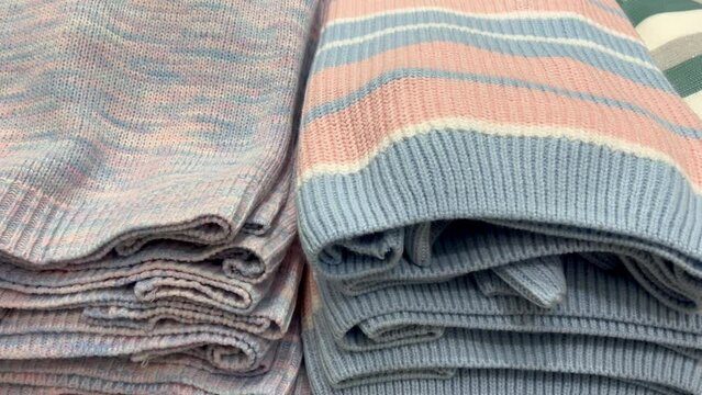 stacks of women's colored sweaters on a shelf in a clothing store. knitted pullovers in delicate shades.