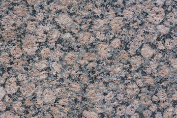 Granite texture. Natural pink granite with a grainy pattern. Stone background. Solid rough surface of rock. Durable construction and decoration material. Close-up.