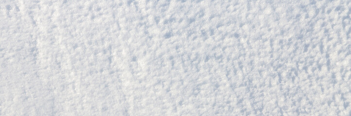 Beautiful winter background with snowy ground. Natural snow texture. Wind sculpted patterns on snow surface. Wide panoramic texture for background and design.