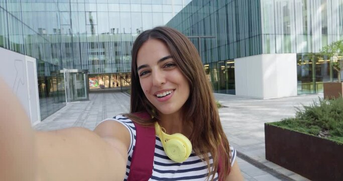 POV of a young student girl waving at the camera while making a video call on a student campus