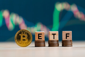 Bitcoin gold coin words ETF wooden blocks on rows stack coins and defocused chart background,...