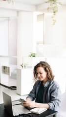 Young Woman Embracing the Modern Work Environment: Using Laptop Computer and Mobile Phone at Office. Student Girl Engaged in Productive Work from Home. Freelancing, Business, E-Learning