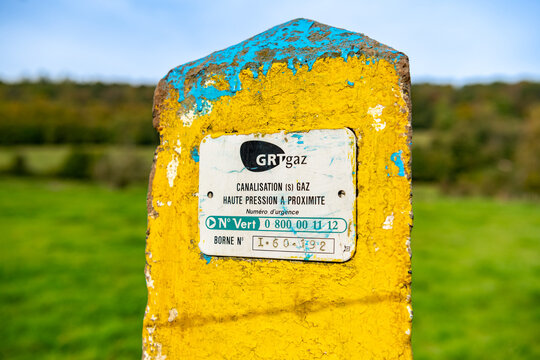 Borne de signalisation jaune et bleu de canalisation de gaz enterr&eacute;e en bordure de champ