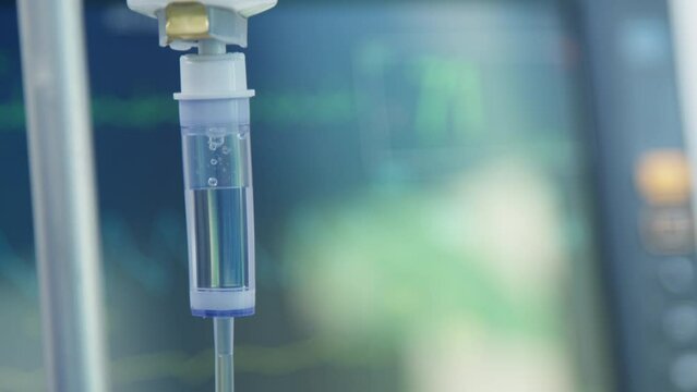 Intravenous drip on the background of a heart rate monitor. The surgeon performs an operation. Modern medicine.