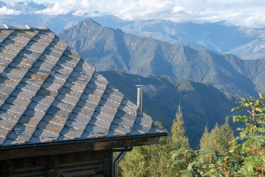 roof with stone tiles, typical of mountain house houses, blue gray granite stones, mountains in background. thermal insulation, energy class.