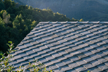 roof with stone tiles, typical of mountain house houses, blue gray granite stones, mountains in...