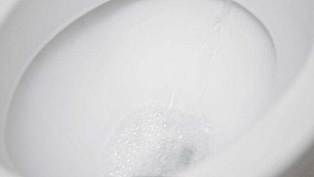Flush toilet. Water flushes the toilet. The flow of water is clearly visible. Slow motion