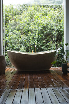 Modern bath by huge window with view on trees in sunny bathroom
