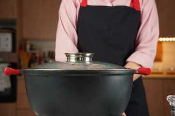 Black cooking pot with a lid on electric hob with boiling water