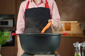 Woman adding fresh carrot at chicken soup, chicken broth, in a pot. Healthy food concept
