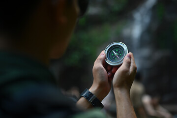 Close up view of male hiker using compass for directions while exploring nature in the forest