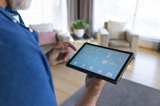 Midsection of senior caucasian man using tablet with smart home interface