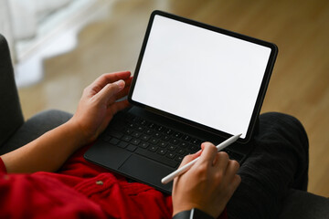 Fototapeta na wymiar Casual male freelancer sitting on sofa in living room and working online on digital tablet
