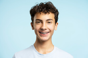 Portrait of smiling boy with braces looking at camera isolated on blue background. Dental, health care concept