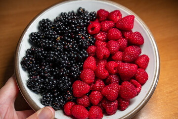 Summer berries, raspberries, blackberries. Dessert on a white plate. Vitamins, healthy nutrition. Fresh raspberries and blackberries on plate lined with symbol of yin and yang