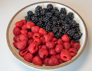 Summer berries, raspberries, blackberries. Dessert on a white plate. Vitamins, healthy nutrition. Fresh raspberries and blackberries on plate lined with symbol of yin and yang