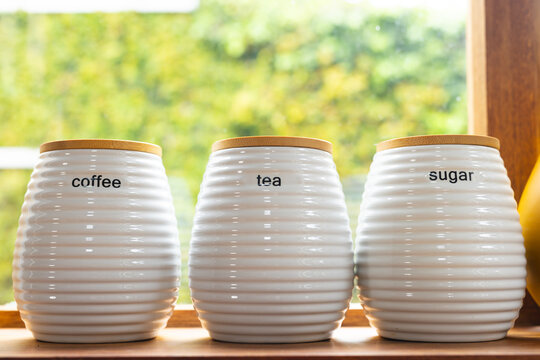 Matching coffee, tea and sugar storage jars on windowsill in kitchen, copy space