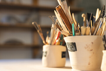 Close up of pottery tools in clay cups in pottery studio