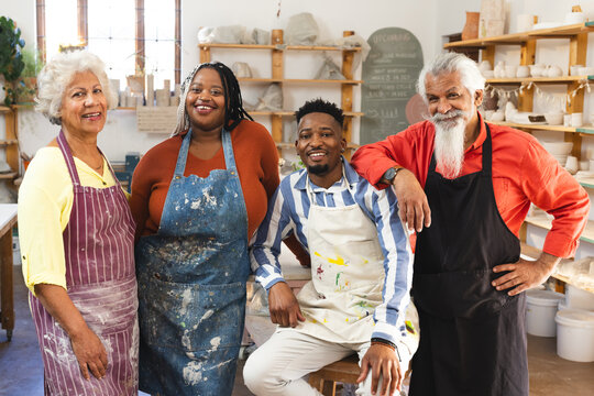 Happy diverse group of potters standing and smiling in pottery studio