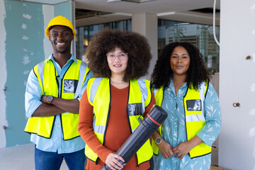 Three diverse casual businesspeople wearing vests and standing in renovated office, copy space