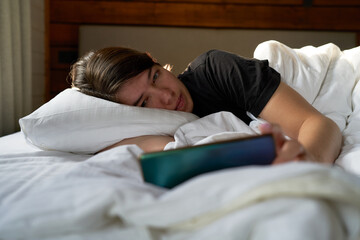 Woman in bed checking social media with smartphone