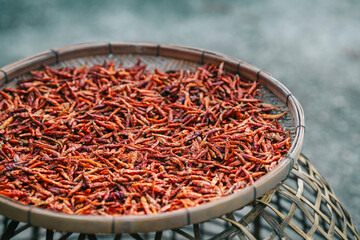 Ripe red chilies that are dried in wooden baskets to be used as a seasoning in food in Thailand.