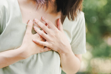 Asian woman has chest pain so she holds her hand to her chest in pain. Health care concept. - obrazy, fototapety, plakaty