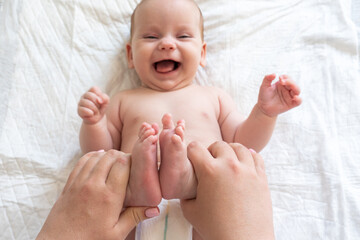 Playful interactions with baby's small feet. Concept of the joys of motherhood - obrazy, fototapety, plakaty