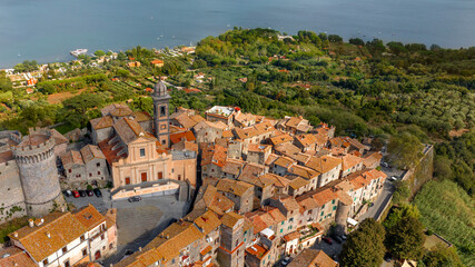 Aerial view of the collegiate church of Santo Stefano Protomartire. It is the cathedral of the town of Bracciano, in the metropolitan city of Rome, Italy. It overlooks Lake Bracciano. - obrazy, fototapety, plakaty