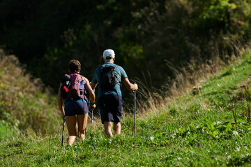 Sommerlich gekleidetes Paar beim Aufstieg &uuml;ber einen schmalen Bergpfad