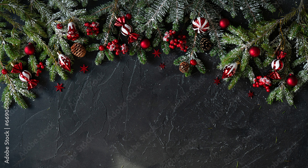 Poster beautiful dark christmas background with a border of fir branches and red decorations. black backgro