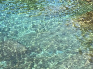 Sea crystal clear water surface with stones and algae at the bottom. 