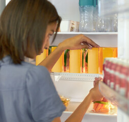 Woman in kitchen arranging food in fridge with care, ruler and ocd behavior, symmetry and anxiety....