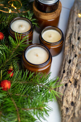 Obraz na płótnie Canvas Soy candles burn in glass jars. Comfort at home. Candle in a brown jar. Scent and light. Scented handmade candle. Aroma therapy. Christmas tree and winter mood. Cozy decor. Festive garland decoration