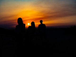 Silhouette of three people outdoors at sunset.