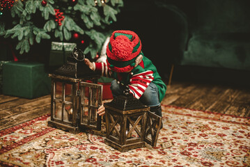 Little child under Christmas tree. baby boy in Santa Claus hat with gifts under Christmas tree with...