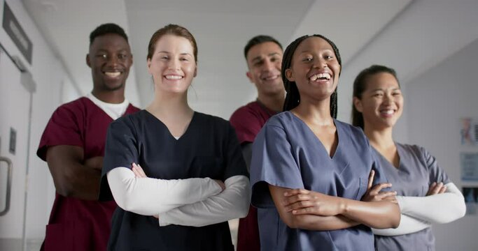 Portrait of happy diverse male and female doctors wearing scrubs in hospital, slow motion