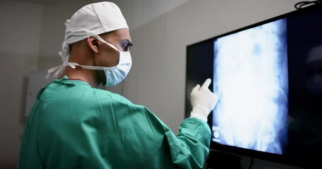 Biracial male surgeon looking at with x-ray scans in operating theatre at hospital, slow motion
