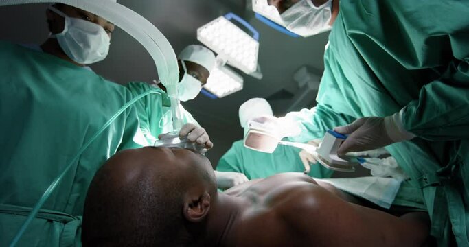 Diverse surgeons using defibrillator on patient in operating theatre at hospital, slow motion