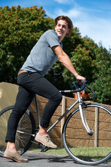 Naklejka premium Thinking, street and a man with a bicycle for cycling, travel or a break on the weekend. Smile, idea and a person or teenager with a bike in road for a ride, commute or transport in the neighborhood