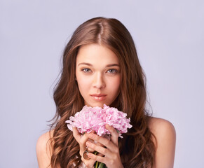 Woman, portrait and bouquet for beauty in studio, wellness and skincare for care, makeup and cosmetic. Female model person, flowers and face for luxury, organic and aesthetic by purple background