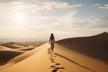Woman treks barefoot in Namibias desert, facing the towering dunes ahead