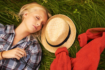 Woman, sleep and rest on grass in nature to relax, peace and calm on field, outdoors and spring. Female person, eyes closed and nap on plants, dream and fashion on holiday, meadow and vacation