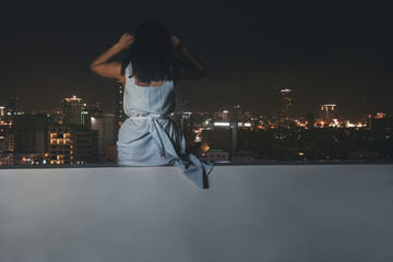 Fototapeta na wymiar A young beautiful woman on a rooftop at nighttime. Perfect for fashion, lifestyle, and cityscape concepts.