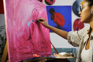 Blurred african american artist painting on canvas in art workshop
