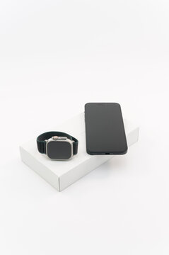 immagine editoriale illustrativa primo piano di Apple Watch Ultra 2 e Apple iPhone 15 Plus con scatola di vendita su superficie bianca
